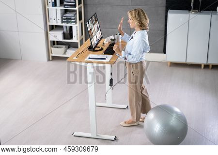 Woman Using Adjustable Height Standing Desk In Office For Good Posture