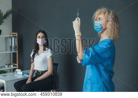 Curly-haired Nurse Preparing Coronavirus Vaccine For Woman Patient At Vaccination Center. Coronaviru