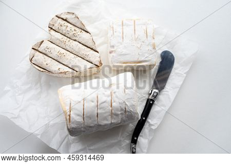 French Cheeses Heartshaped, Squared And Cylindrical Neufchatel Cow Cheese With Mold On White Paper,