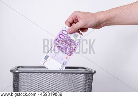 The Hand Throws Five Hundred Euros In The Trash. The Concept Of The Devaluation Of The Euro.