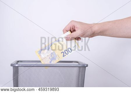 The Hand Throws Two Hundred Euros In The Trash. The Concept Of The Devaluation Of The Euro.