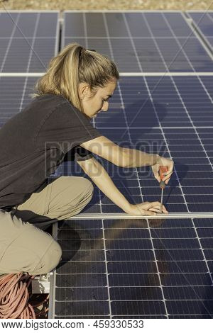Top View Of Young Woman Screwing A Screw To Assamble The Photovoltaic Solar Panels On The Roof Of A 