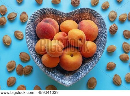 Ripe Apricots And Peaches In Heart-shaped Plate On Blue Background. Flat Lay