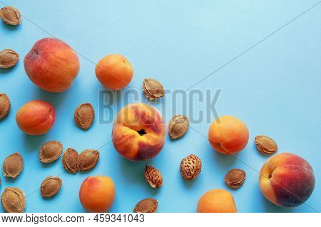 Ripe Apricots And Peaches  And Apricot Stones On Blue Background. Flat Lay, Copy Space