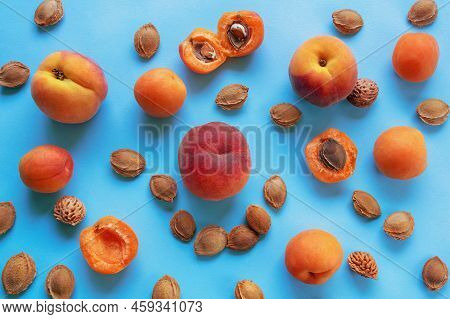 Bright Ripe Apricots And Peaches And Fruit Stones On Blue. Flat Lay