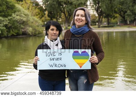 Love Is Never Wrong. Cheerful Queer Couple Holding A Message Supporting The Lgbt Community