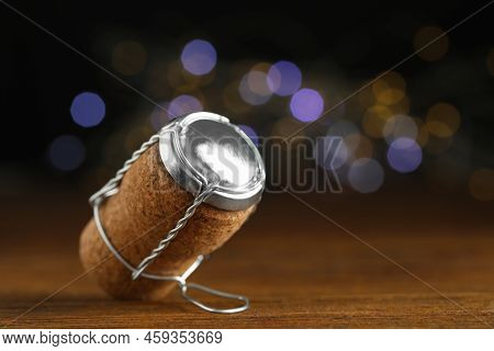 Sparkling Wine Cork With Muselet Cap Against Blurred Festive Lights, Closeup. Space For Text