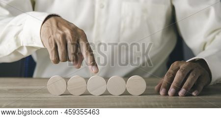A Young Businessman Pointing To A Wooden Block On His Desk With Determination,