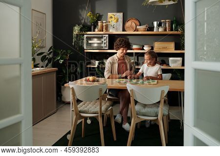 Young Woman And Her Youthful Daughter Playing Board Game Togather