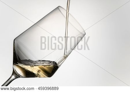 Close-up Of Pouring White Wine Into A Crystal Glass. Filling White Wine Into A Crystal Glass Isolate