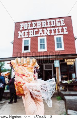 Polebridge, Montana - July 3, 2022: Hand Holds Up A Famous Huckleberry Bear Claw Pastery From The Me