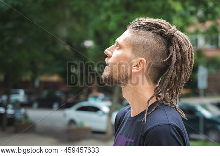 Side View Of A Caucasian Man With Dreadlocks And Sidecut On A Summer Street