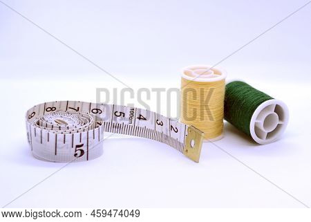 Threads And Sewing Ruler. In The Photo, The Threads Are Yellow And Green And A Sewing Meter.
