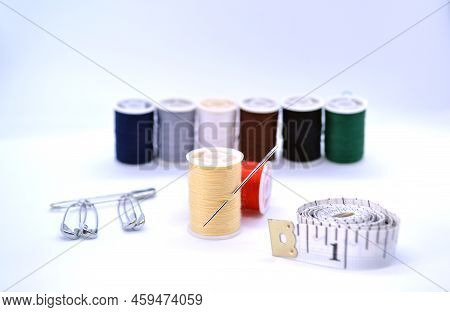 Sewing Accessories. The Photo Shows Colored Threads, A Needle, A Sewing Ruler And Pins.