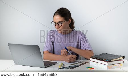 A Woman With A Laptop, Books, Notebooks, Notebooks At The Table Makes Notes - Online Learning, Remot