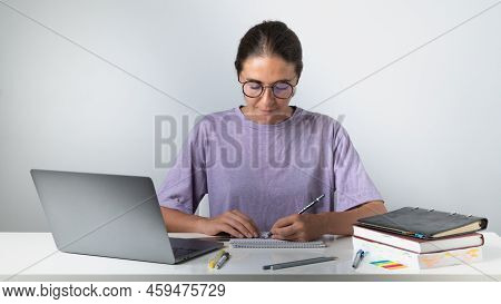 The Student Draws With A Pencil And A Ruler, On The Table A Laptop, Textbooks And Notebooks. High Qu