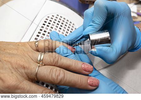 The Manicurist Applies A Topcoat With Black Dots To The Finished Hybrid Nails With A Brush.