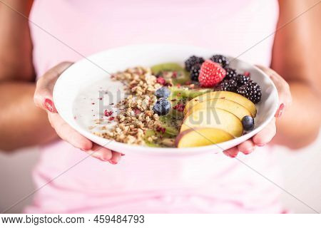 Yogurt, Blackberry Muesli, Raspberries, Blueberries, Kiwi And Peaches In A White Bowl Holding Young 