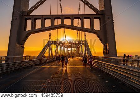 May 1, 2022. Florianopolis, Brazil. Hercilio Luz Cable Bridge With Walking People And Sunset Sky In 