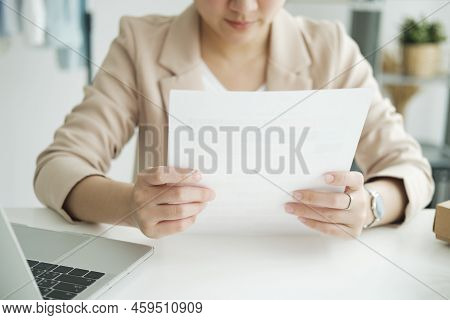 Young Asian Female Freelan Sit Reading Report On Paper In Online Clothing Store..
