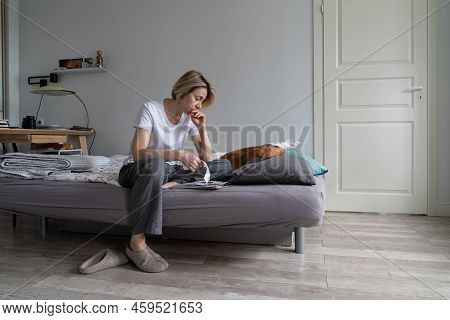 Unhappy Depressed Middle-aged Woman Living Alone With Dog Sits On Bed Counting Bills. Female Thinks 