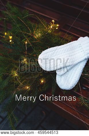Merry Christmas Lettering. Branches Of A Coniferous Tree Decorated With A Garland Lie On A Bench Alo