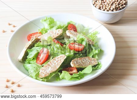 Front View  Of Tempeh Or Tempe Salad With Tomato And Green Vegetable In White Plate And A Bowl Of So