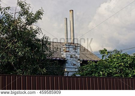 Two Old Long Gray Chimney Pipes On A Gray Slate Roof Against A Sky