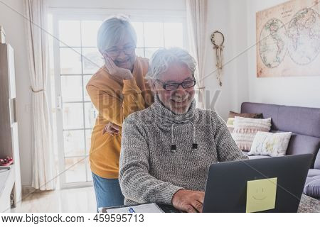 Couple Of Two Happy Seniors Working And Using Laptop Together At Home Smiling And Having Fun Togethe