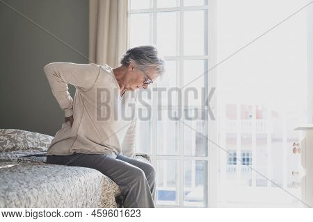 Tired Senior Woman Suffering From Backache After Sleep, Rubbing Stiff Muscles, Old Female Sitting On