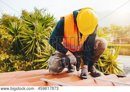 Technical Worker Works With Drill On The Roof Of A House