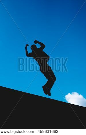 Black Silhouette In The Air Of A Man Doing An Extreme Somersault With The Sky In The Background.