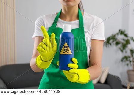 Woman Showing Bottle Of Toxic Household Chemical With Warning Sign, Closeup