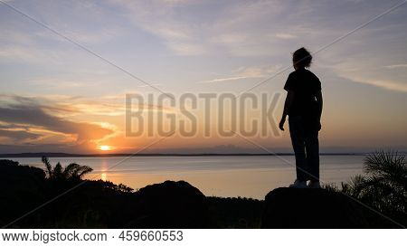 Kalangala, Uganda - May 10, 2022: Standing Girl Watching Colorful Sunset Near Kalangala (ssese Islan