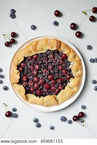 Fresh Cherry And Blueberry Galette With Coconut On White Plate, Top View. Homemade Rustic Dessert - 
