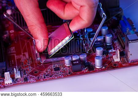 A Man's Hand Inserts A Processor Into The Motherboard Chipset.
