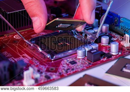 A Man's Hand Inserts A Processor Into The Motherboard Chipset.