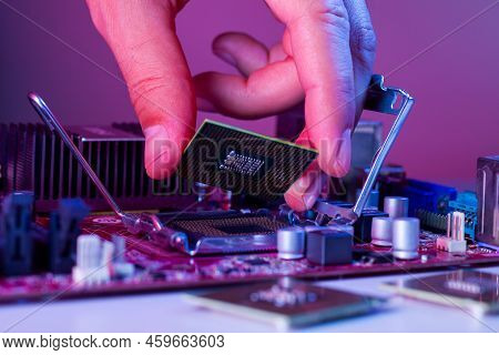 A Man's Hand Inserts A Processor Into The Motherboard Socket.