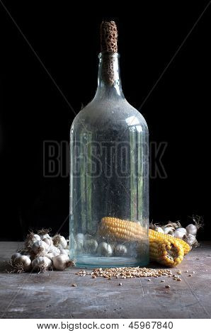 Oude fles met knoflook en maïs
