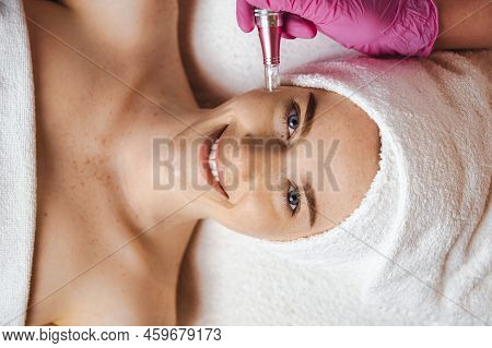 Smiling Freckled Woman Patient Receiving Procedure Microdermabrasion Of The Facial Skin In A Beauty 
