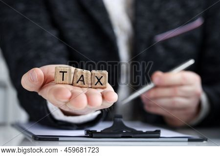 Close-up Of Man Holding On Palm Tax Word Collected Of Wooden Blocks Letters. Government, State Taxes