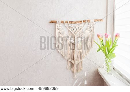 Handmade Macrame Wallhanging. 100% Cotton Wall Decoration With Wooden Stick Hanging On A White Wall.
