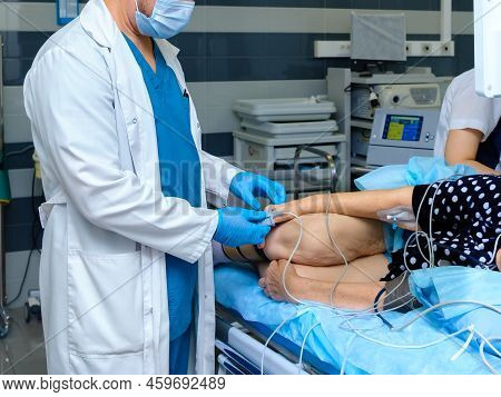 The Doctor Puts A Pulse Oximeter On The Finger Of An Elderly Woman. A Doctor In A Mask And Gloves Pr