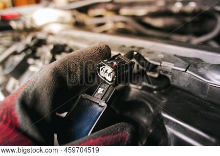 The Auto Mechanic Is Unplugging The Ignition Coil Of The Car Engine In The Engine Compartment.