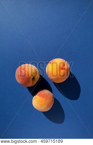 Three Fresh Ripe Peaches On A Blue Background With Shadows, Vertical Orientation With Copy Space. To