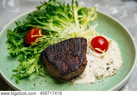 Culinary Mistake. A Piece Of Overcooked And Burnt Beef Meat On Salad Leaves With Cherry Tomatoes And