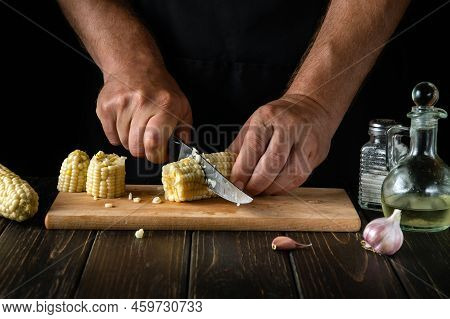 The Chef Cuts The Boiled Maize With A Knife. Corn Is An Excellent Dietary Breakfast Or Lunch. Workin