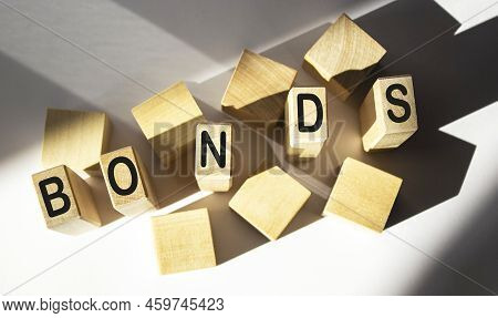Wooden Blocks With The Word Bonds On A White Background. A Bond Is A Security That Indicates That An