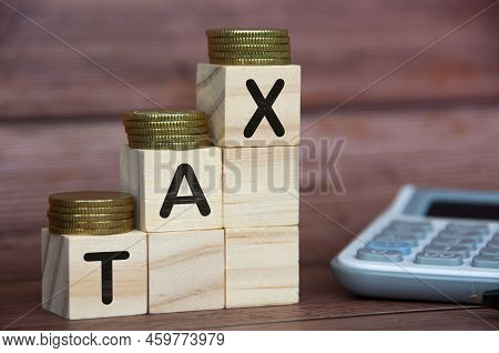 Tax Word On Wooden Blocks With Gold Coins On Top And Calculator Background. Tax Concept.