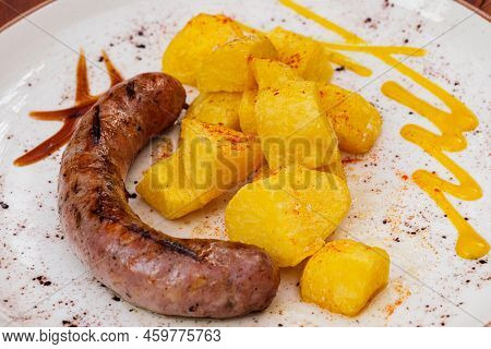 Spanish Pork Sausages Butifarras With Fried Potatoes And Sauces On White Plate.